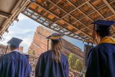 在红岩露天剧场，三名戴着帽子、身穿长袍的学生排队领取毕业证书.