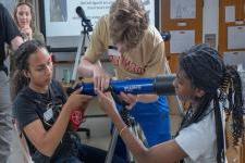 Three students work together on a telescope 
